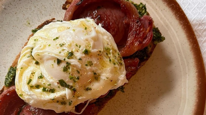 A breakfast toast with pesto, mutton and a poached egg 