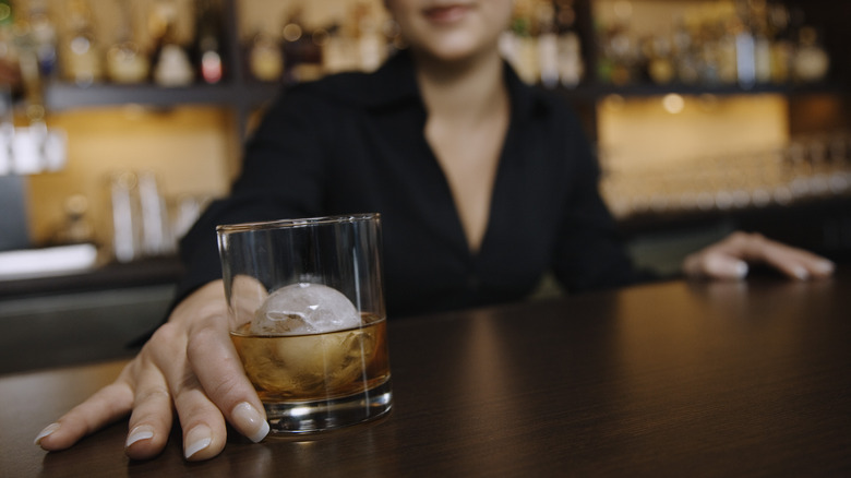 Bartender hands customer a drink