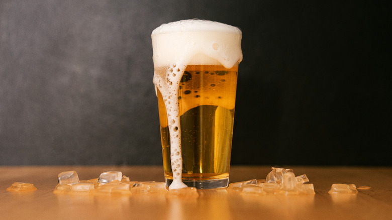 Beer on a table with ice cubes scattered around it