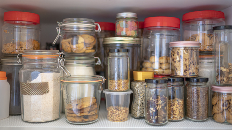 Multiple glass jars and plastic containers in a pantry