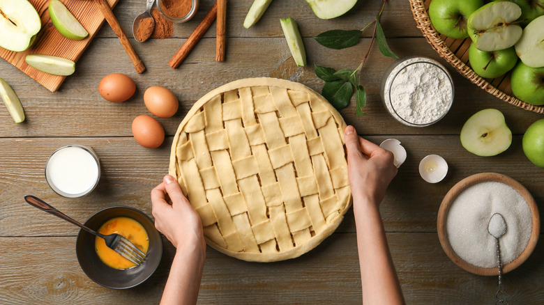 A fresh apple pie being assembled with a lattice top