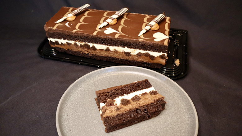 A slice of cake on a plate with a full cake in the background