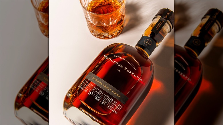 Bottle of Woodford Reserve Masters Collection Sonoma Triple Finish with glass