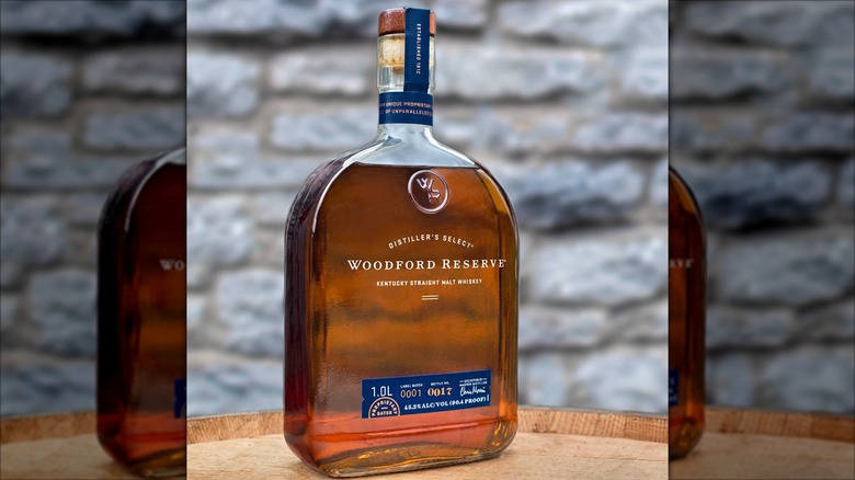 Bottle of Woodford Reserve Malt Whiskey on wood table with stone background