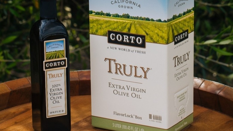 A bottle and a box of Corto olive oil displayed on a wooden table