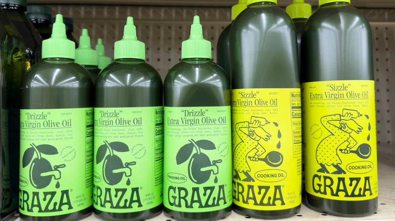 Several bottles of Graza "Drizzle" and "Sizzle" olive oils on a grocery shelf