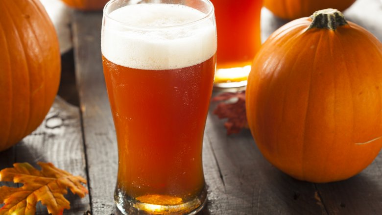 glass of beer near pumpkins