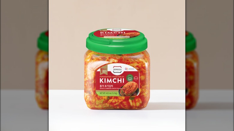 A jar of Jongga kimchi on a white table with a beige backdrop