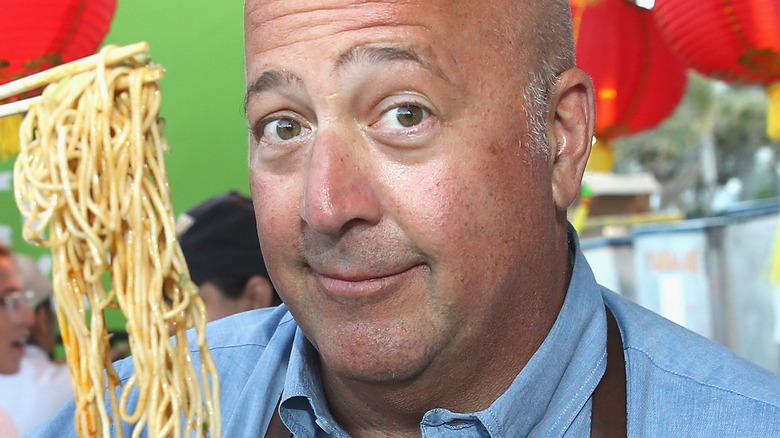 Andrew Zimmern holding noodles