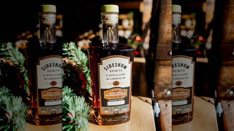 Sideshow Spirits Double Barrel bourbon bottle on wood table with pine decorations