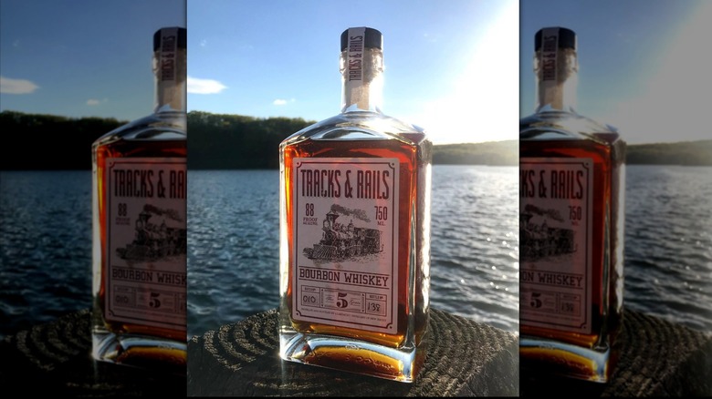 Tracks and Rails Five Grain bourbon with water and hills in background