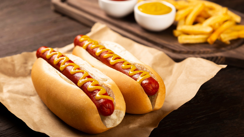 Hot dogs with mustard in buns next to fries