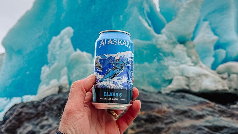 Hand holding a can of Alaskan Class 5 pale ale, in front of a glacier