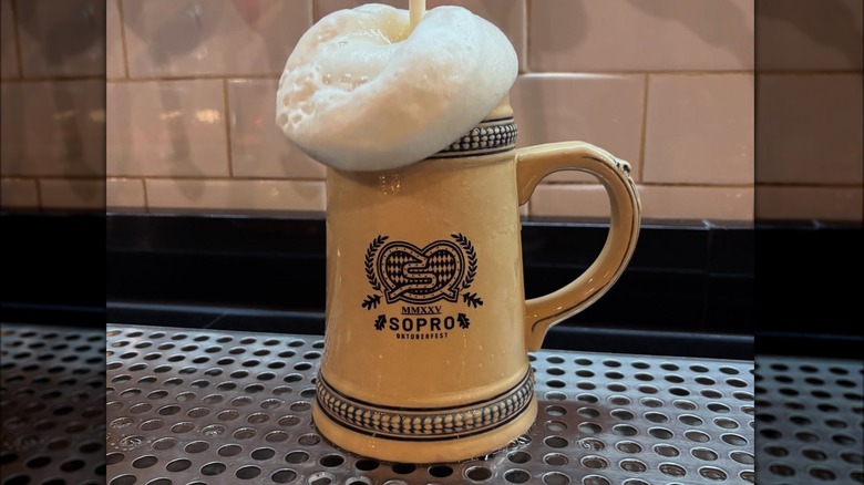 Traditional German-style beer mug with foam on top with a logo in the middle and the words "MMXXV SOPRO OKTOBERFEST"