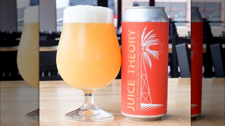 A glass of beer alongside an orange beer can that reads "Juice theory, hazy IPA with citra, nectaron and krush cryo