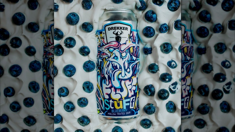 A colourful drekker Fluff Stuff Blueberry Mallow Fruited Sour can partially submerged in cream and blueberries