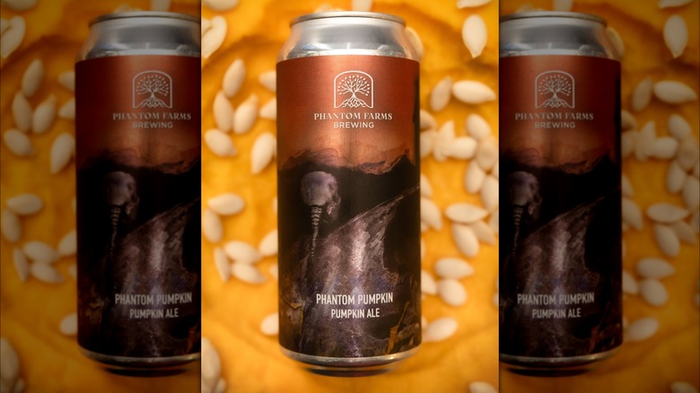A beer can in a brown and black color palette with a design of a skeleton from behind walking on a road with mountains on the background, that reads "Phantom Farms Brewing Phantom Pumpkin ale"