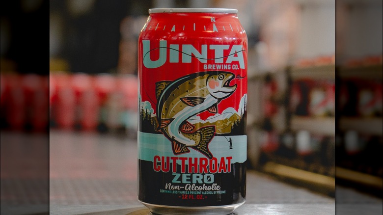 A Cutthroat zero non-alcoholic beer can, with an ilustration of a cutthroat trout leaping out of water on a blue lake, with mountains on the background and a red sky