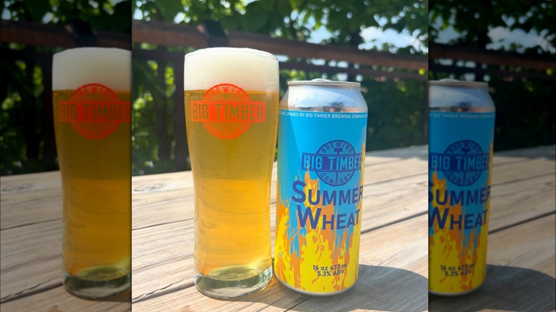 To the left, a pint of Big Timber Brewing Company beer, with the logo in red. To the right, a light blue can with a design of flames engulfing half of it. The letters, on dark blue, read: Big Timber Brewing Company Summer Wheat