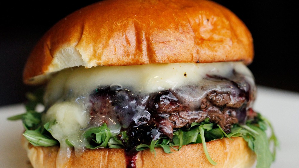 Burger with melted cheese, lettuce and blueberry sauce.