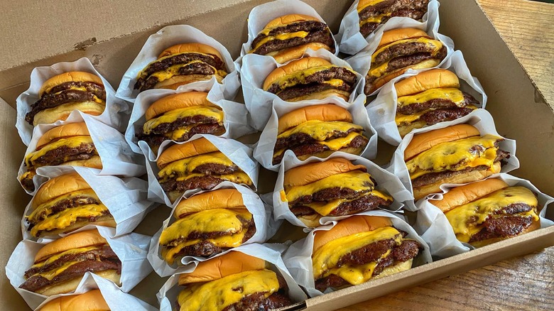 cardboard box full of smash burgers with cheese in paper wrappers from Burger Yum in Pennsylvania