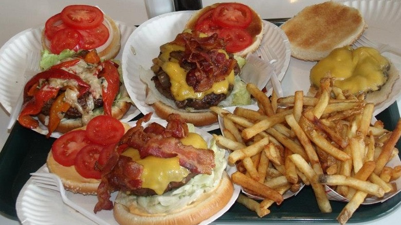paper plates with cheeseburgers, bacon, red peppers, and fries