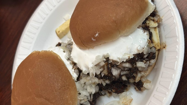 two burgers with diced onions and marshmallow fluff on top served on paper plate