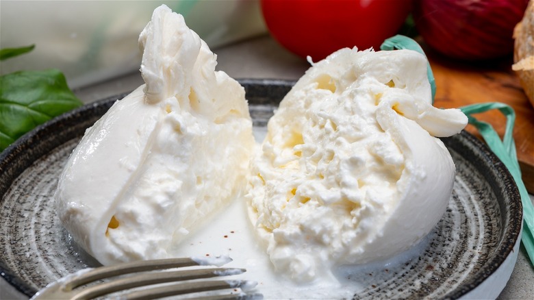 Burrata cut open on a plate with a fork