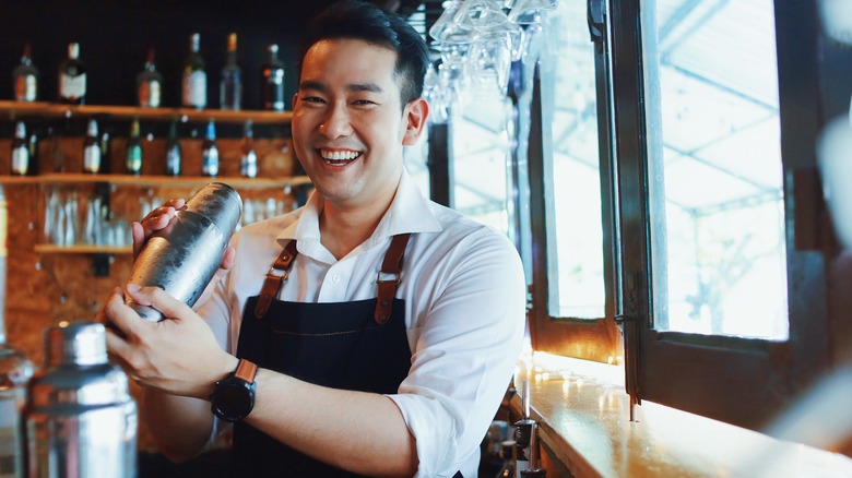 smiling bartender shaking drink