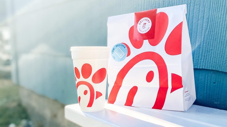 a chick fil la to-go bag and drink on a white table