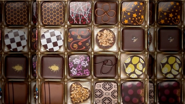 Gold box insert holding artistic gourmet chocolates.