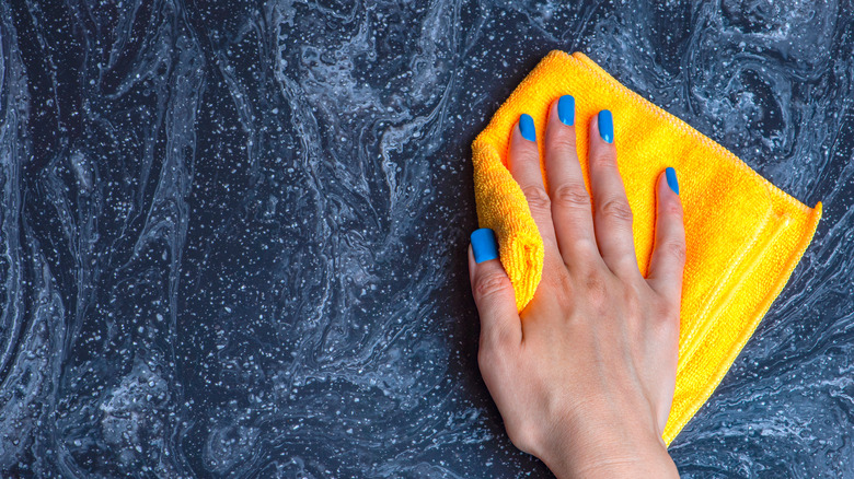 hand with towel cleaning counter