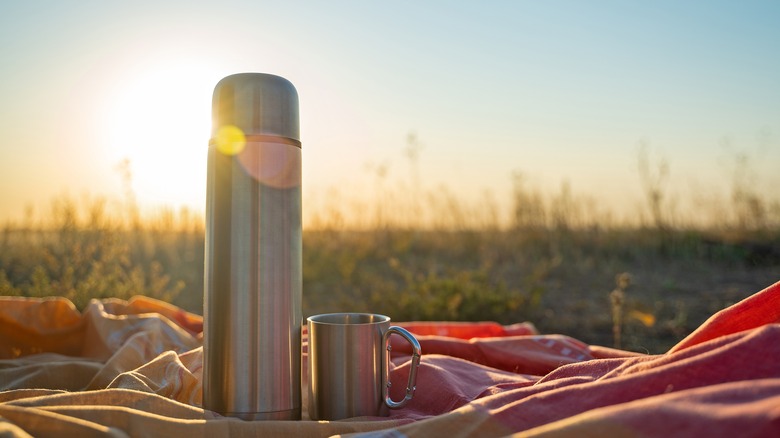 Coffee thermos against sunrise