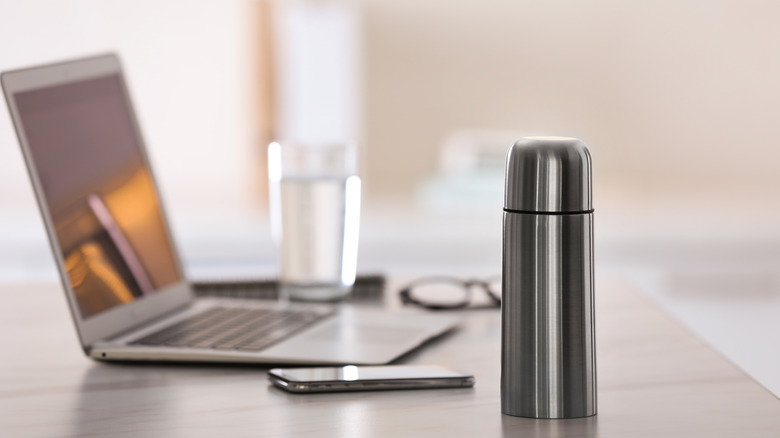 Coffee thermos next to laptop