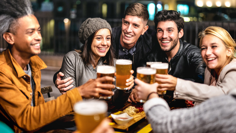 college age young adults cheers with beers