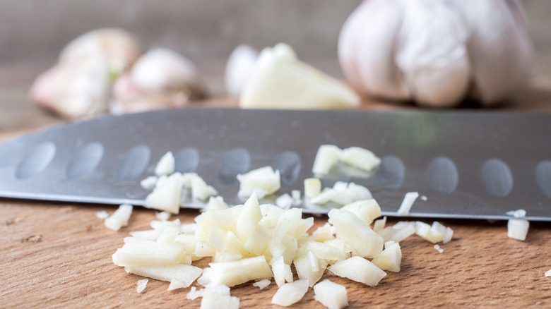minced garlic with knife on cutting board
