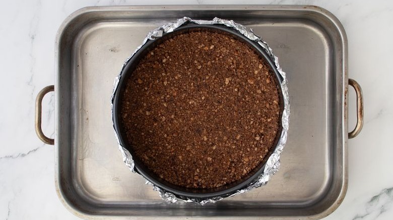 Cheesecake crust in springform pan inside of larger roasting pan