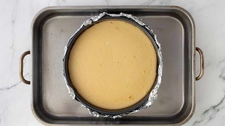 Baked cheesecake in pan inside of larger roasting pan