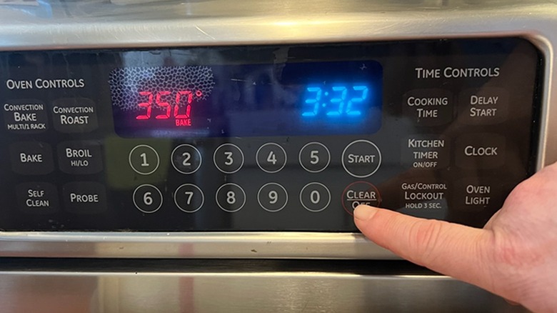 Finger pressing off button on oven control panel