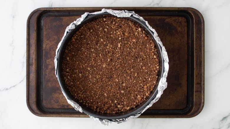 Cheesecake crust in springform pan sitting on baking sheet