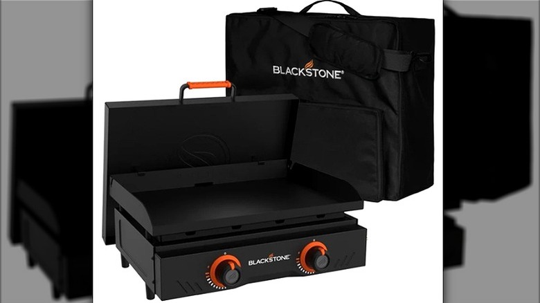 Blackstone portable grill open with carrying case positioned behind it.