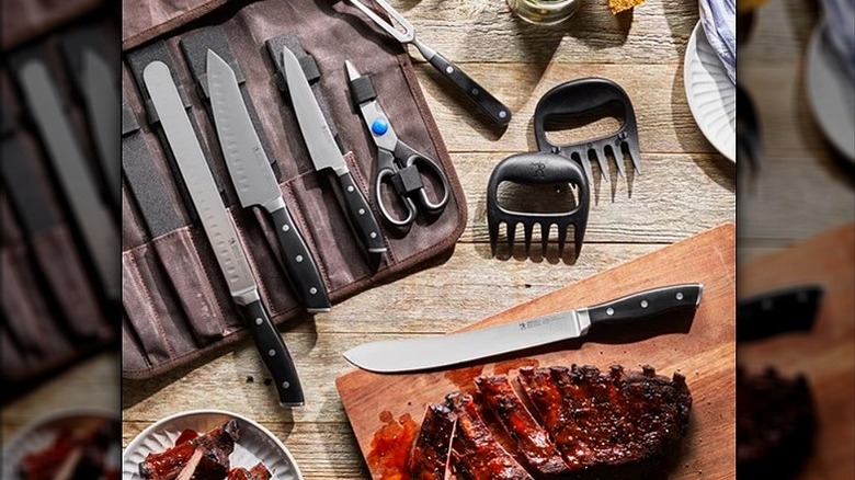 Multi-piece barbecue set from Henckels with carrying bag, knives, and other tools on wood table with grilled steak on cutting board.
