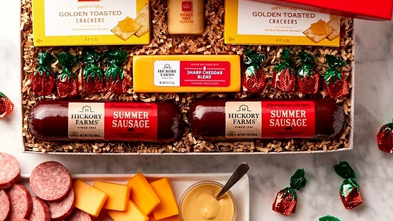 Open Hickory Farms gift box containing meats and cheese with tray of food sitting in front of it.