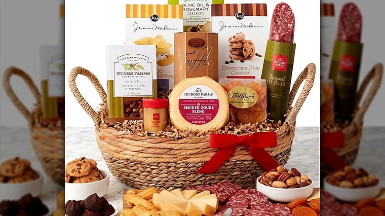 Hickory Farms gift basket with cheeses, meats, crackers, and other foods. Hors d'oeuvres are spread out in front of the basket.