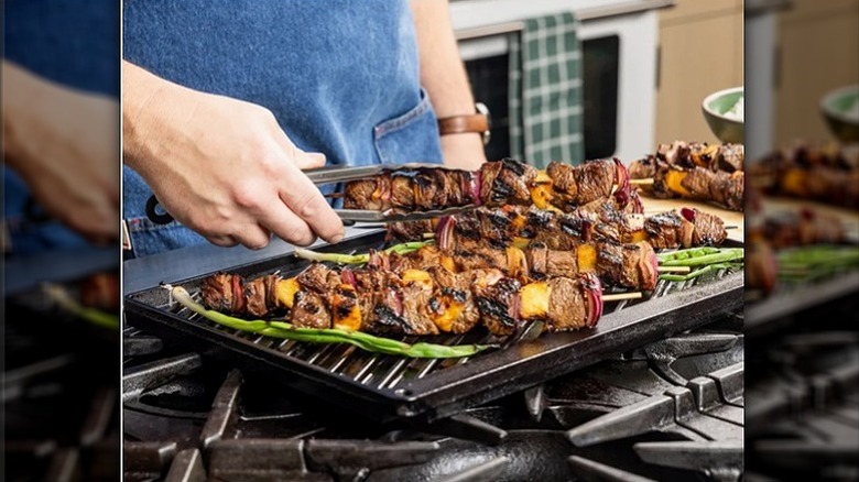 Lodge cast iron reversible grill and griddle with steak kebabs and veggies on stovetop