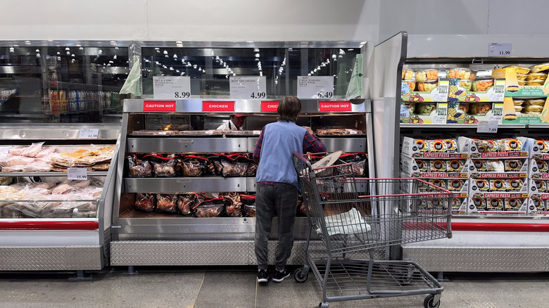 A Costco shopper browsing the rotisserie chickens