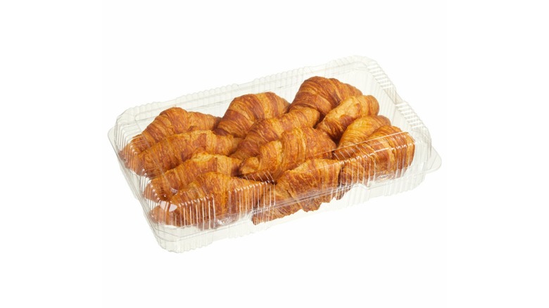 A plastic container of classic croissants on a white background