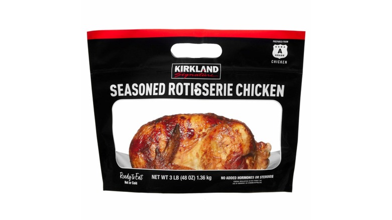 A Kirkland brand rotisserie chicken in a black bag on a white background