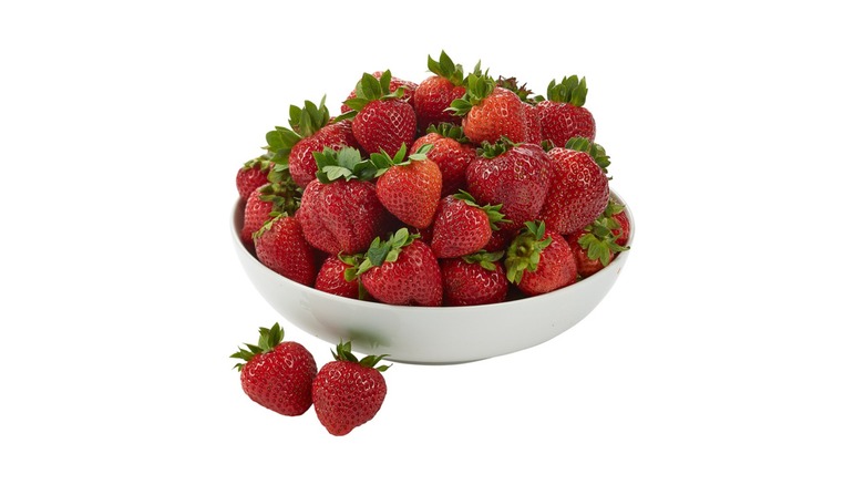 A white bowl of fresh strawberries on a white background