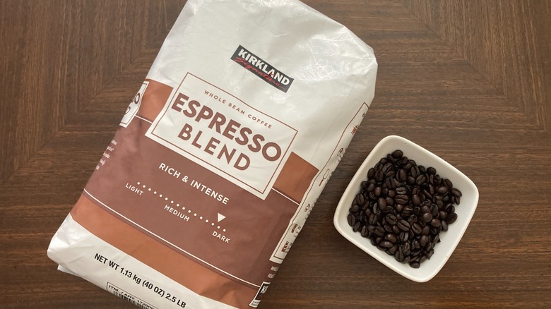 Bag of Kirkland espresso blend on table with dish of coffee beans